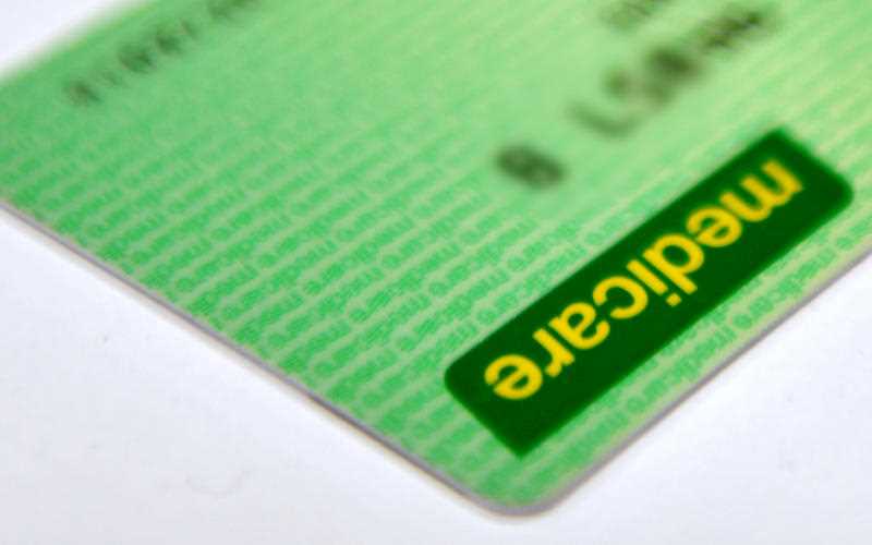 A section of a green and yellow Australian Medicare card is seen on a white background