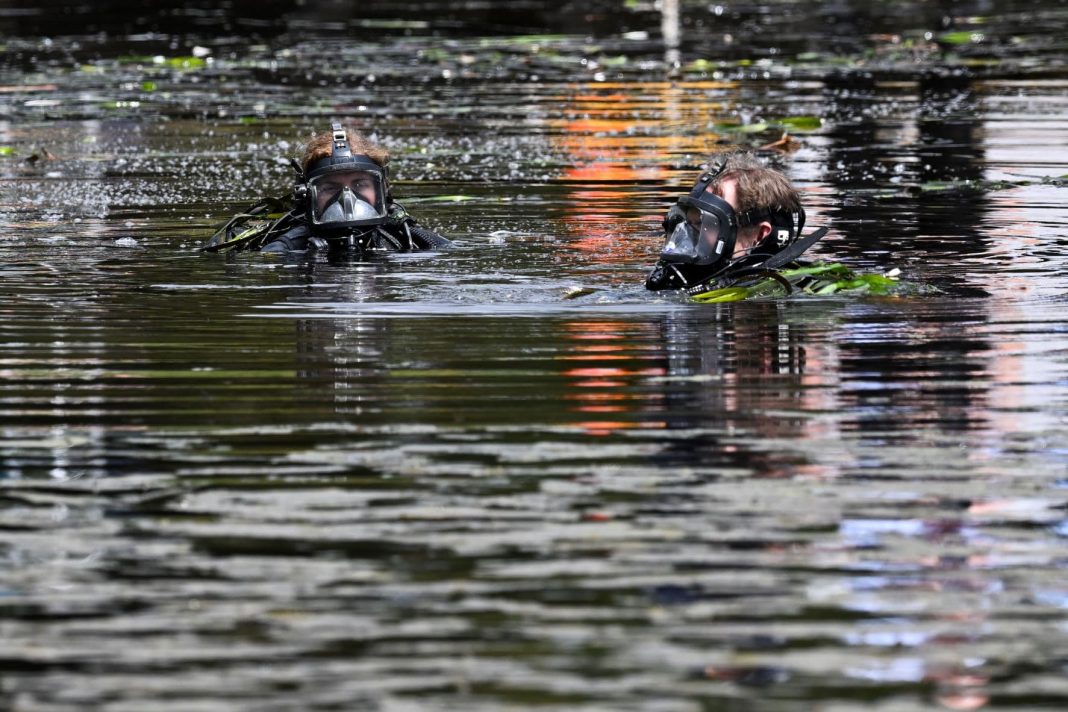 Police divers search an area at Yerrabi Pond, Gungahlin in Canberra, Saturday, November 5, 2022. Canberra police have launched a major investigation after human bodies were discovered in a suburban lake near a skate park and BMX track