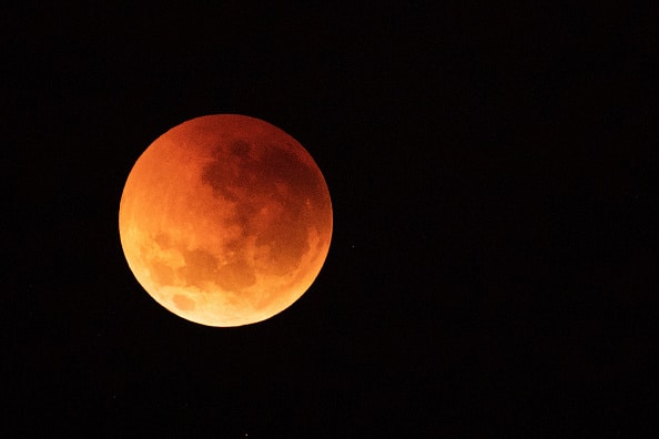 The moon is seen turning red in the sky over Sydney during a total lunar eclipse on July 28, 2018