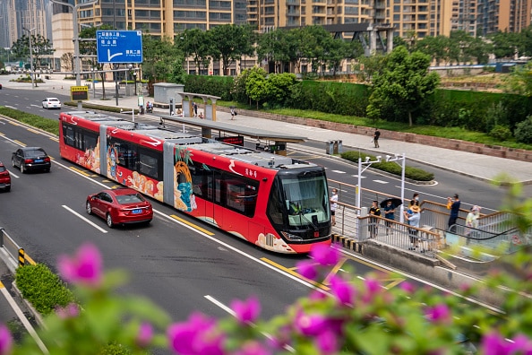 A red 'Shudu' trackless light rail vehicle stops at a station in Chengdu, Sichuan Province of China.