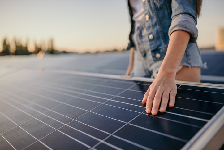 Young woman touching solar panels at power station