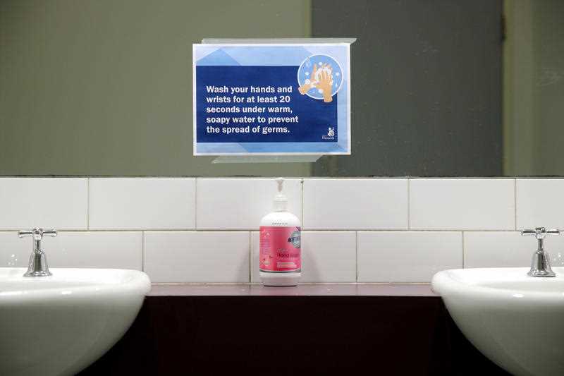Hand sanatizer and a hand washing message is seen in a public bathroom