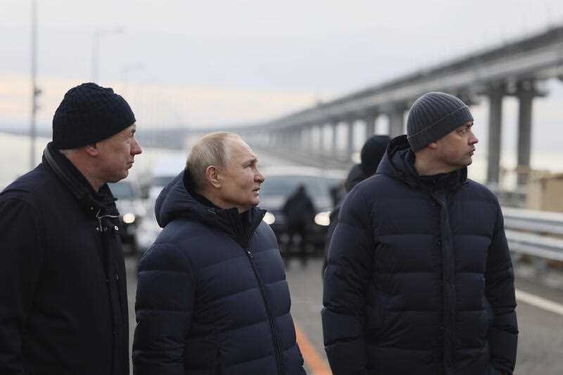 Russian President Vladimir Putin, center, and Deputy Prime Minister Marat Khusnullin, left, visit the Crimean Bridge connecting Russian mainland and Crimean peninsula over the Kerch Strait, which was damaged by a truck bomb attack in October