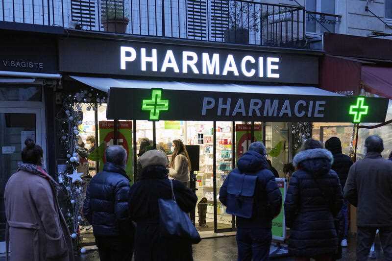 People wait in front of a pharmacy in Paris, France