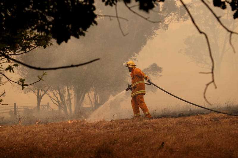 A CFS firefighter battles a fire as it runs across a paddock in the Adelaide Hills