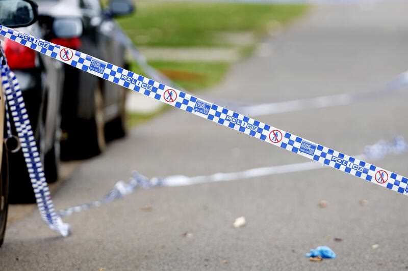 blue and white check police tape stretched across a road