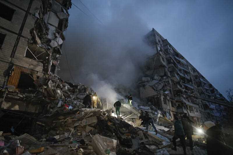 Local residents clear the rubble after a Russian rocket hit a multistory building leaving many people under debris in Dnipro, Ukraine, Saturday, Jan. 14, 2023