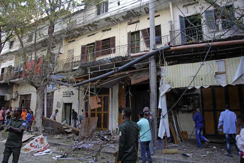 People gather outside their destroyed shops after a suicide bomber detonated at the Banadir regional administration in Mogadishu, Sunday, Jan.22, 2023.