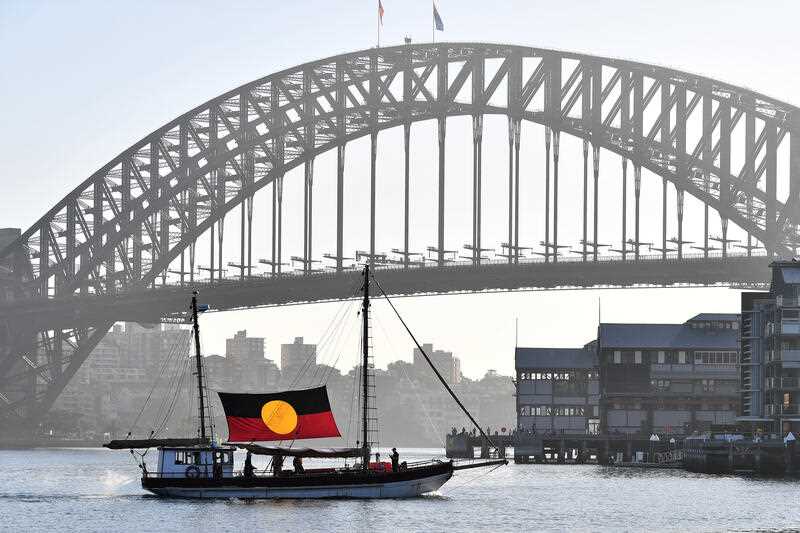 Tribal Warrior arrives to Barangaroo Reserve with ceremonial firE during the WugulOra Morning Ceremony on Australia Day 2023 celebrations at Walumil Lawns in Sydney, Thursday, January 26