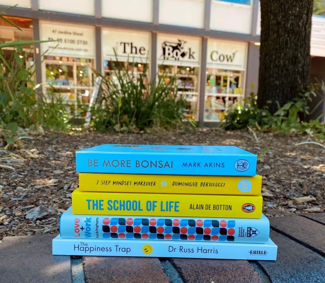 A bundle of 5 wellbeing books stacked outside of The Book Cow bookshop in Kingston, ACT