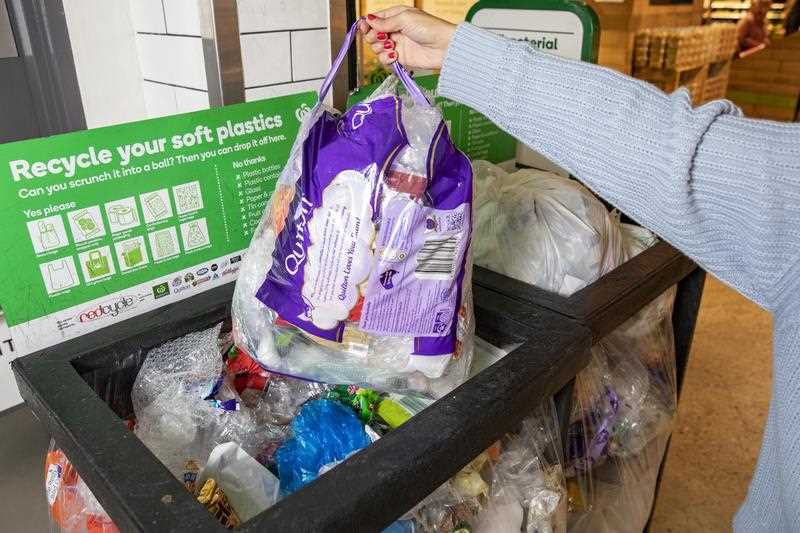 person seen placing bag of soft plastics in recycling bin