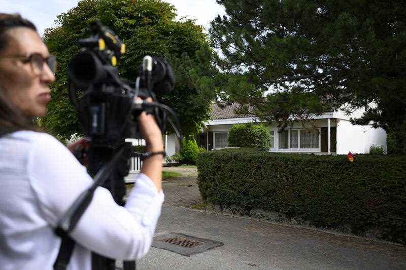 A film camera operator outside a suburban house