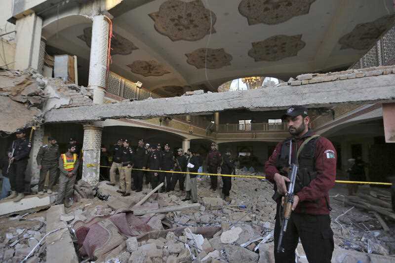 Police officers examine the site of Monday's suicide bombing after authorities finished the rescue operation, in Peshawar, Pakistan, Tuesday, Jan. 31, 2023