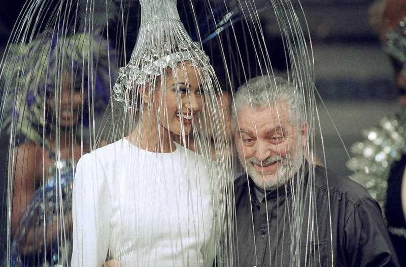 Spanish fashion designer Paco Rabanne poses with a model wearing a white dress with a metallic headpiece after presenting his 1992/93 fall-winter haute couture collection in Paris, France, on July 29, 1992