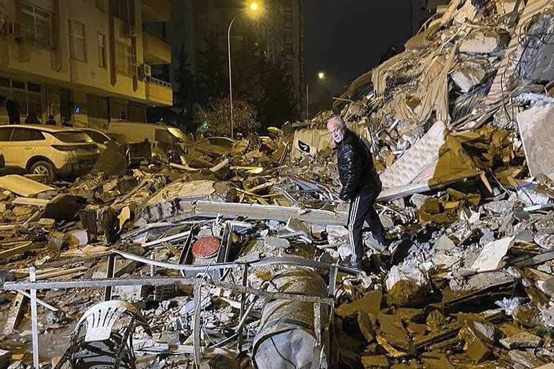 a man searches collapsed buildings in Diyarbakir, southern Turkey, early Monday, Feb. 6, 2023 after a powerful earthquake caused significant damage