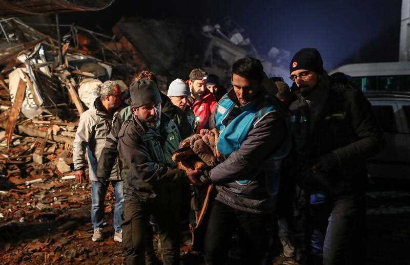 People carry wounded man from collapsed building in Turkey
