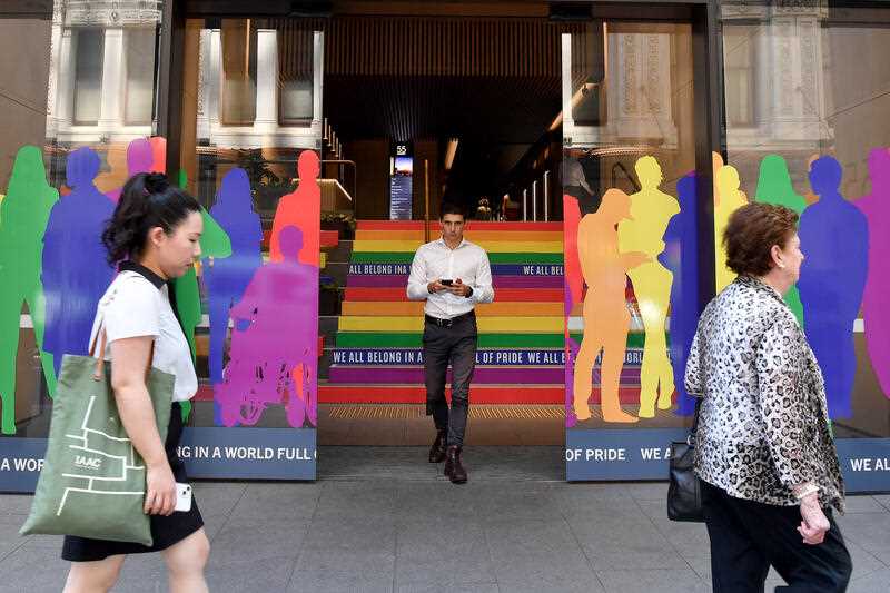 Workers walk past an office building that is decorated in the colours of the Pride Flag ahead of Sydney WorldPride 2023, in Sydney, Thursday, February 16, 2023