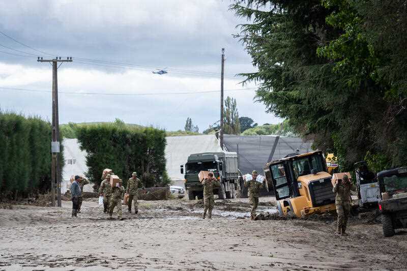 New Zealand Defence Force soldiers carry supplies to Moteo Marae, near Puketapu on the banks of the Tutaekuri River