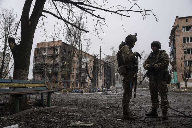 Ukrainian marine servicemen stand on a street in front of the residential building which was heavily bombed by Russian forces, at the frontline city of Vuhledar, Ukraine, Friday, Feb. 25, 2023