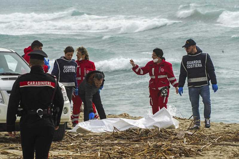 Italian Red Cross volunteers and coast guards recover a body after a migrant boat broke apart in rough seas, at a beach near Cutro, southern Italy, Sunday, Feb. 26, 2023.
