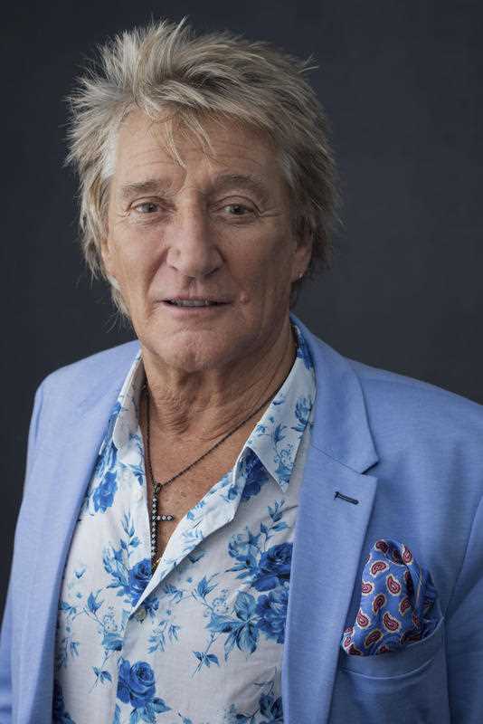 wearing a floral shirt and pale blue jacket Rod Stewart poses for a photo in NYC in 2018