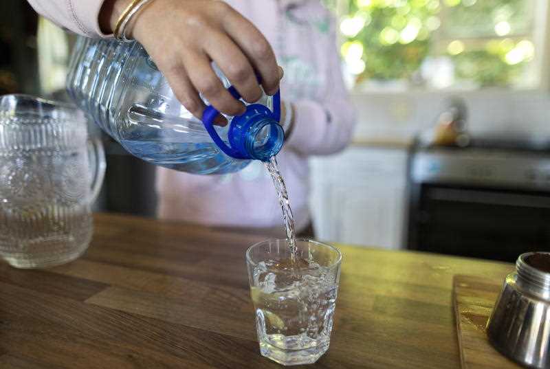 Adult seen filling a glass with bottled water