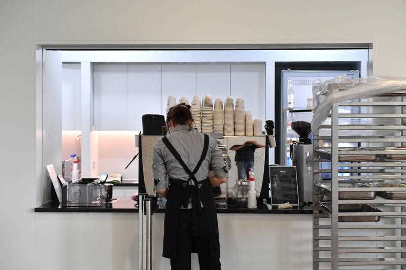 A worker cleans a coffee machine at a cafe
