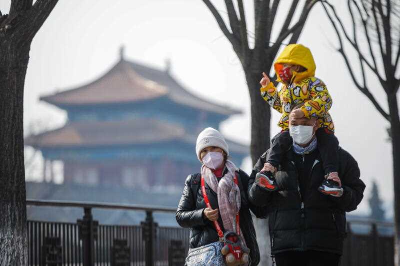Tourists wearing face masks walk near the Turret of the Palace Museum in Beijing, China