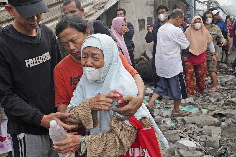 A woman weeps at a neighborhood affected by a fuel depot fire in Jakarta, Indonesia, Saturday, March 4, 2023