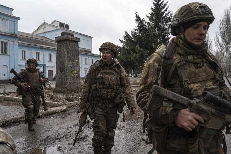 Ukrainian servicemen walk on a street as they just come back from trenches of Bakhmut in Chasiv Yar, Ukraine, Wednesday, March 8, 2023