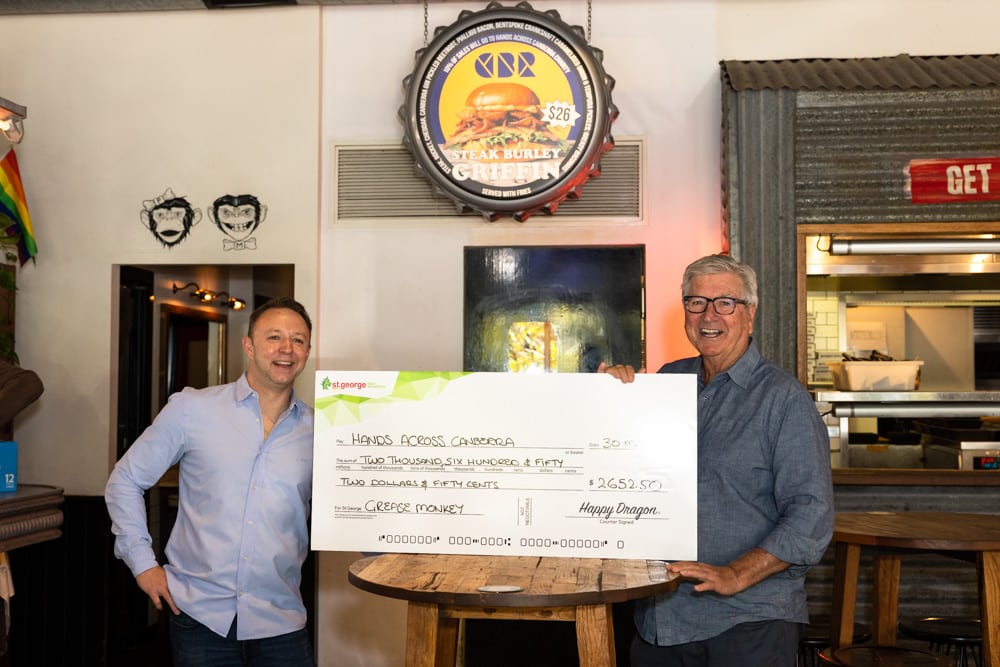two men holding big cheque at Grease Monkey burger joint