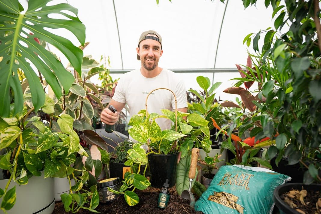 smiling male horticulturist surrounded by pot plants