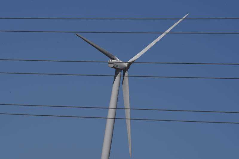 A wind turbine is seen behind electricity lines at a wind farm outside Bungendore near Canberra