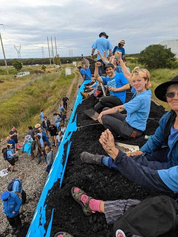 Protesters gesture from atop a stationary coal train during a protest about climate change and thermal coal production at Sandgate, near Port of Newcastle