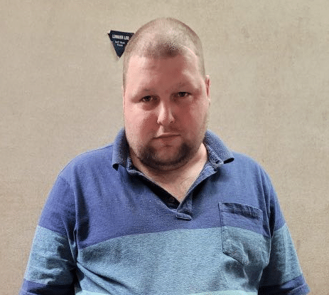snapshot of 33-year-old man John Catling with shaved head wearing blue polo shirt