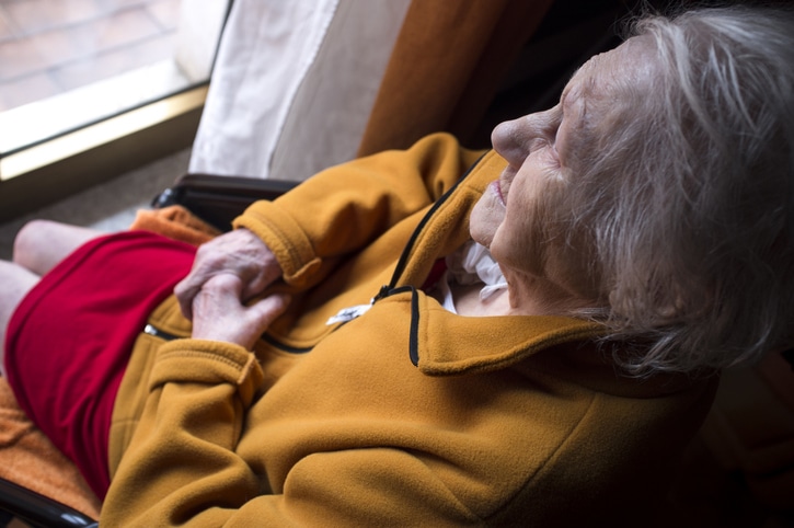 portrait of sad lonely pensive old senior woman looking out a window