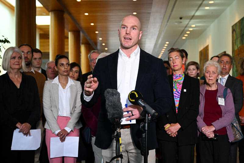 Independent Senator David Pocock is surrounded by community advocates as he speaks to media during a press conference at Parliament House in Canberra