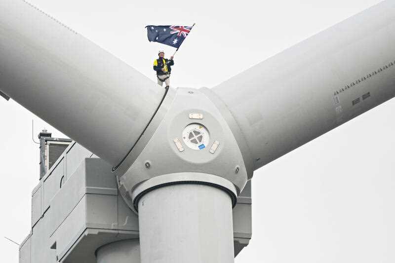 Australian businessman Andrew Twiggy Forrest waves an Australian flag as he stands on top of a wind turbine during the opening of Squadron Energy’s Bango Wind Farm, Boorowa NSW