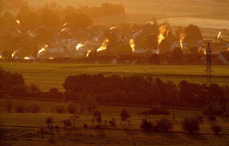 Smoke rises from the chimneys of houses in early morning sunlight