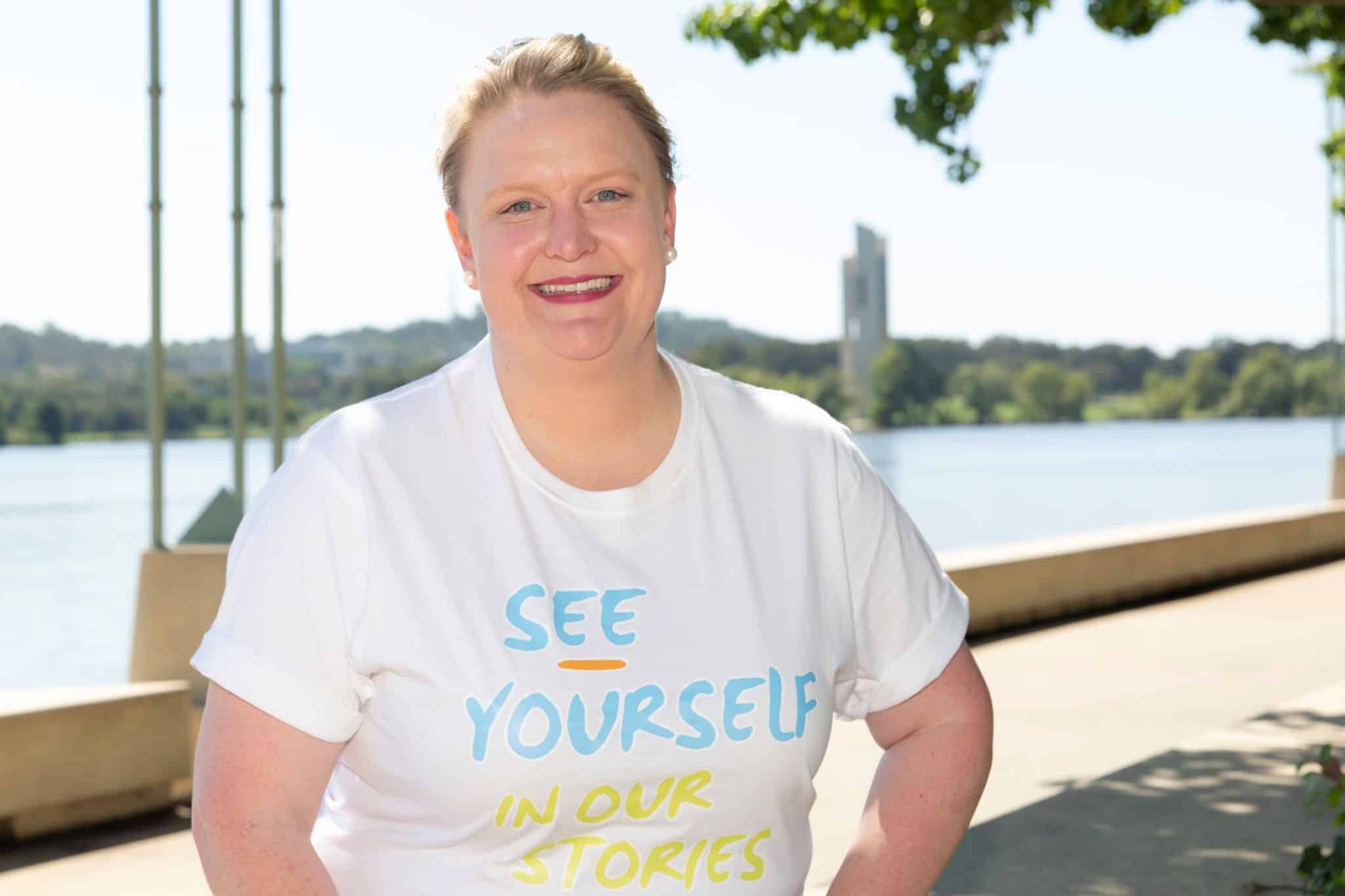 Smiling woman in her 30s Heidi Prowse in a t-shirt standing beside Lake Burley Griffin on a sunny day