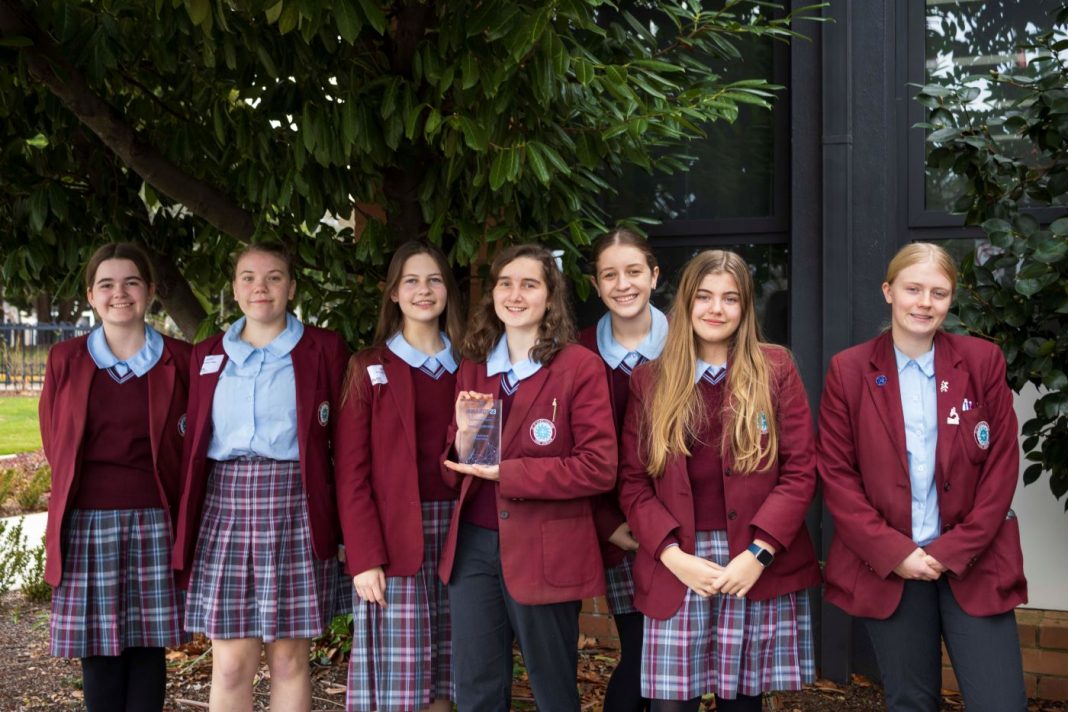 7 young women in St Clare's college uniforms holding a STEM trophy