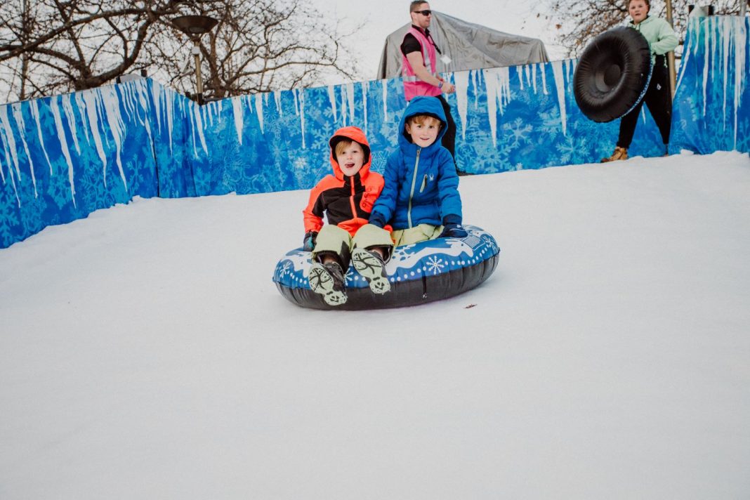 2 kids on toboggan on snow slope at Winter in the City in Canberra city centre