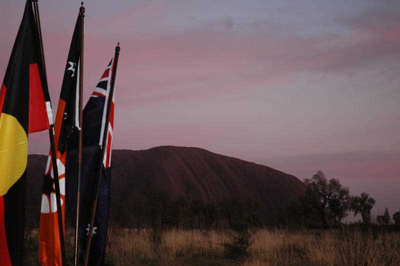 The Aboriginal, Northern Territory and Australian flags are visible before Uluru on a new viewing platform