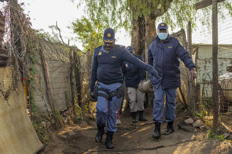 South African police officers remove gas cylinders used by illegal gold miners in the Angelo Informal Settlement in Boksburg, South Africa, Thursday July 6, 2023