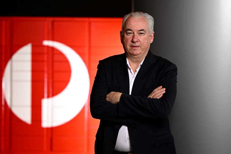 Australia Post Group CEO and Managing Director Paul Graham poses for a photo in front of the Australia Post logo