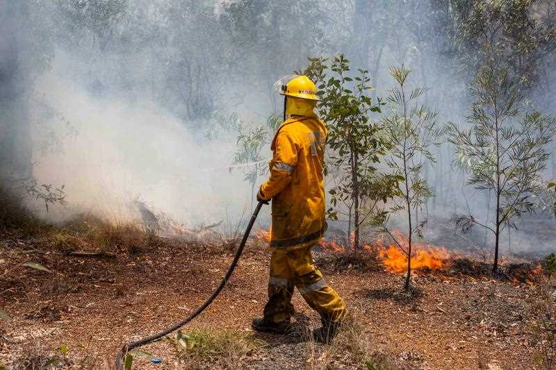 a firefighter in yellow safety gear working to control a bushfire