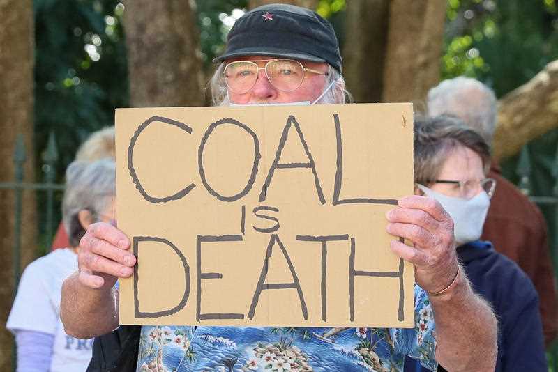 Protesters hold placards during a rally at Queensland Parliament in Brisbane, Monday, August 30, 2021