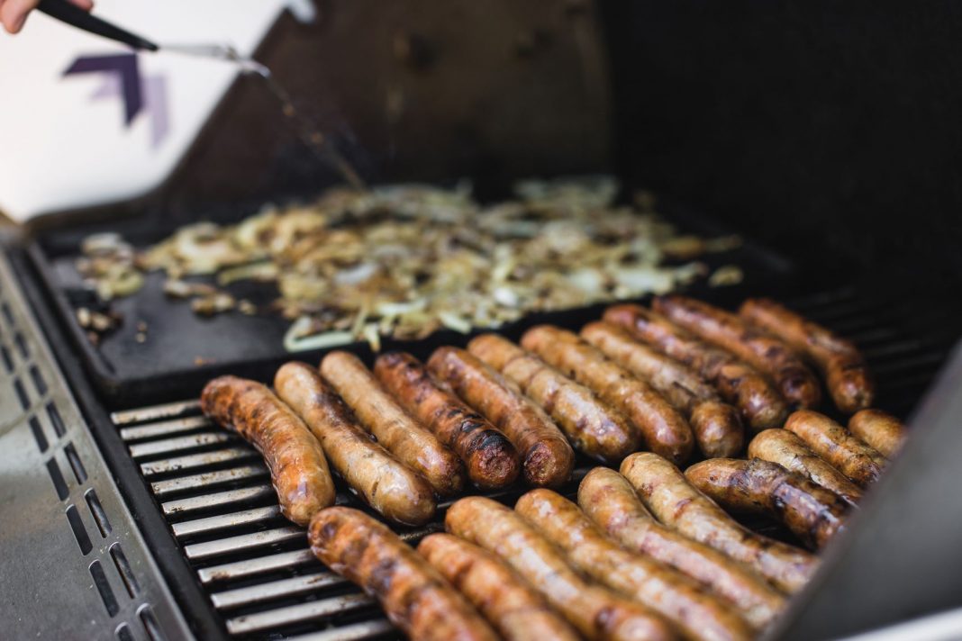 sausages and onions frying on a barbecue grill