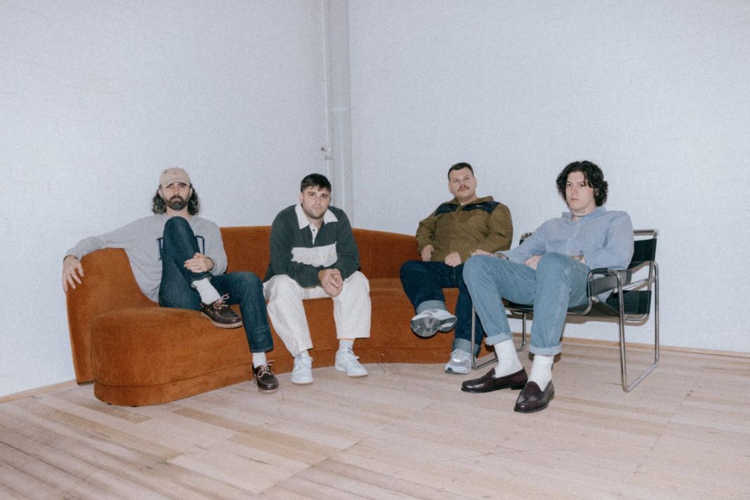 4 male members of post-punk rock band sitting in a lounge room