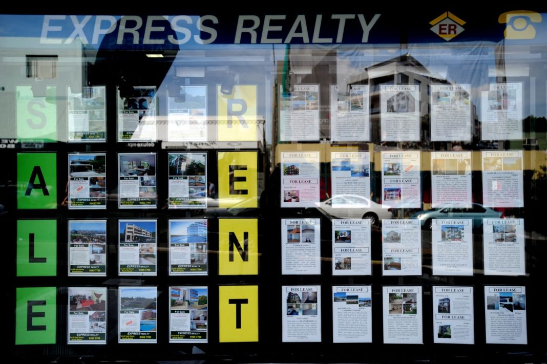 Houses for sale and lease are advertised in the window of a real estate agency in Sydney
